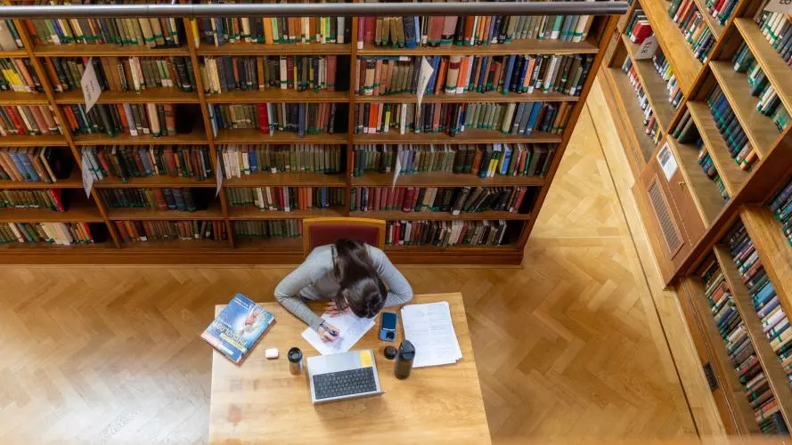Aerial view of a female student working at a desk in the Howard Piper Library at St Hugh's College
