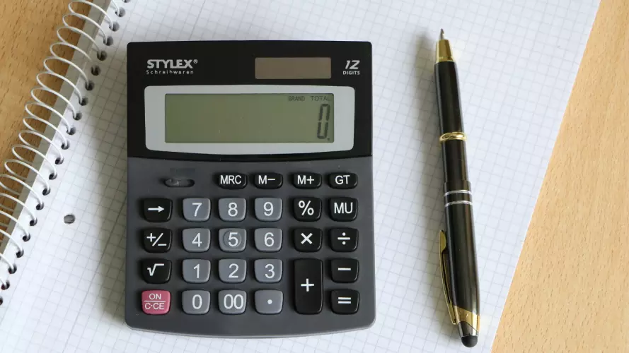 A calculator on a notepad next to a pen